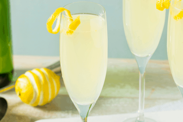 Wine cocktails - French 75 with lemon peel garnish and a lemon in the background