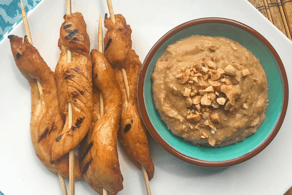 Christmas party food recipes - spicy chicken satay with peanut dipping sauce in bowl beside