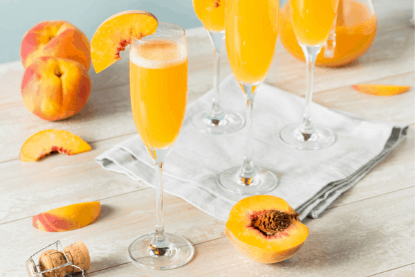 Wine cocktails - Bellini with peaches around on a table with a napkin
