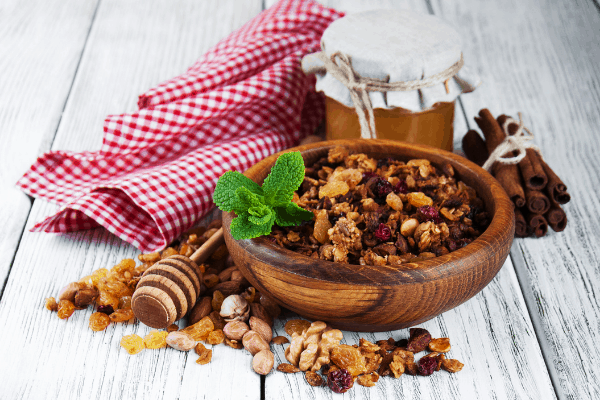 blueberry almond granola - why make your own granola? Bowl of homemade granola with ingredients and a red check tablecloth